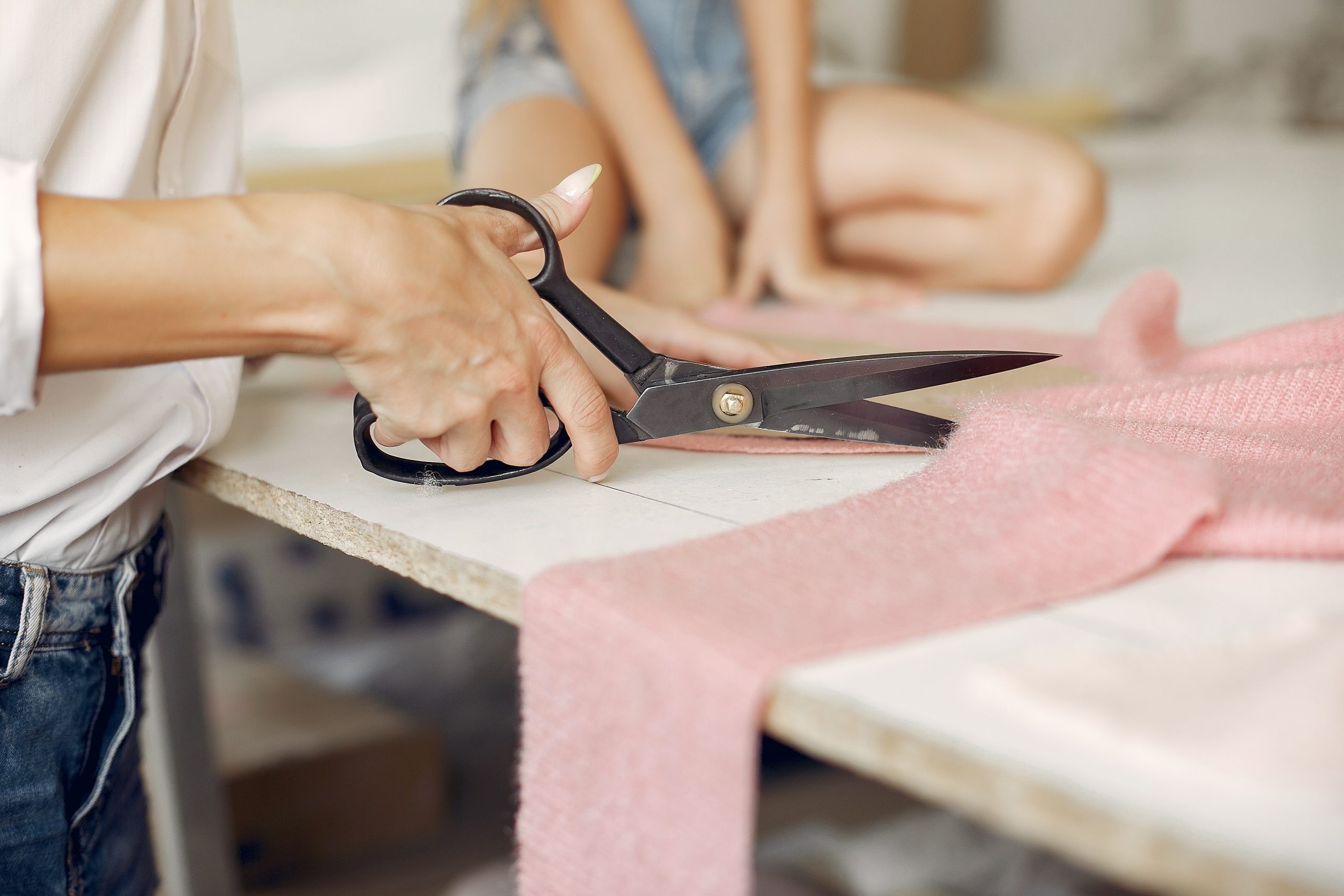 Mother with daughter at the factory. Family with a fabric. Woman use the scissors.