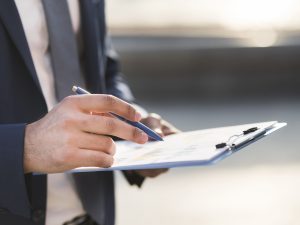 gros-plan-homme-affaires-verification-presse-papiers (1)
