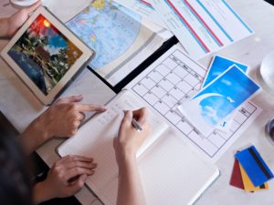 Close-up shot of unrecognizable couple taking necessary notes and planning vacation trip to Europe while sitting at table